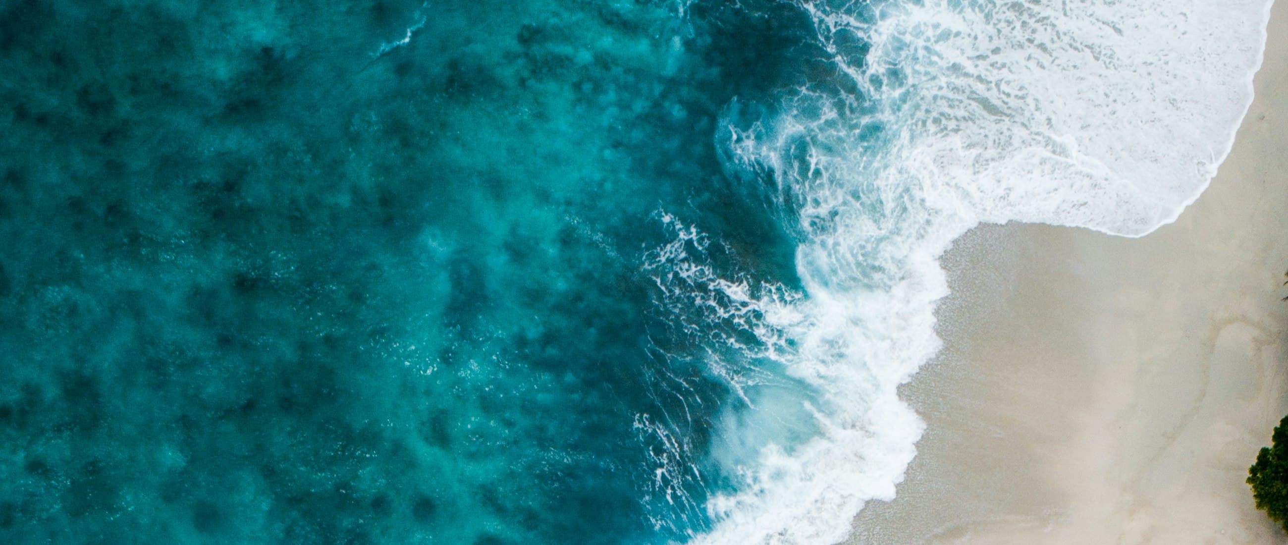 Turquoise ocean waves meeting a sandy beach from above